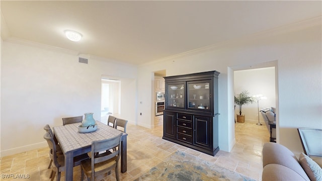 dining room featuring crown molding, baseboards, visible vents, and stone finish flooring