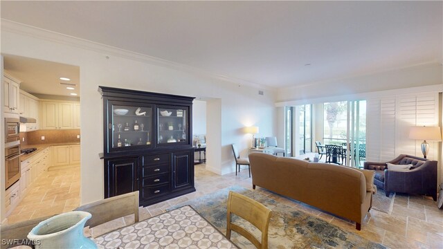 living room featuring recessed lighting, stone finish floor, crown molding, and baseboards