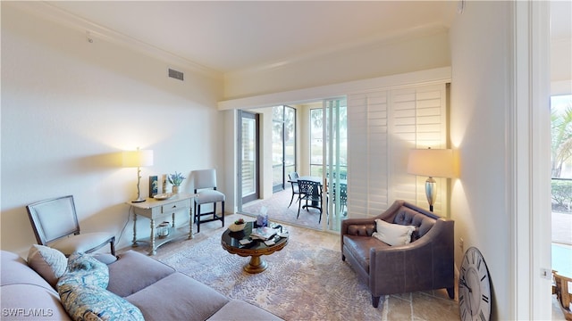 living area with visible vents, a healthy amount of sunlight, and ornamental molding