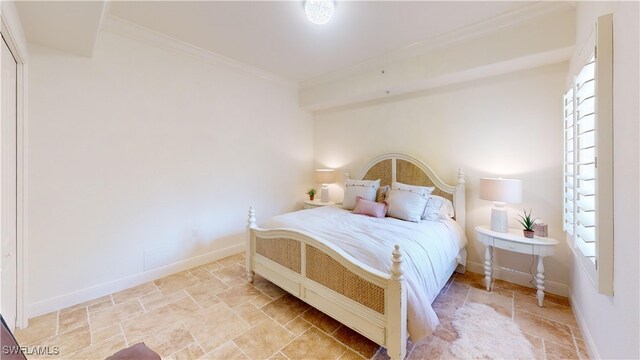 bedroom featuring stone finish floor, crown molding, and baseboards