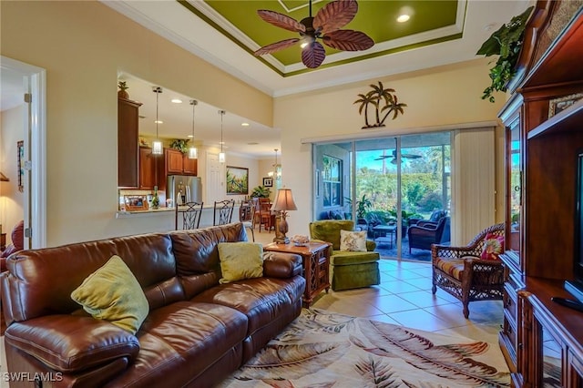 tiled living room with ornamental molding, a raised ceiling, and ceiling fan