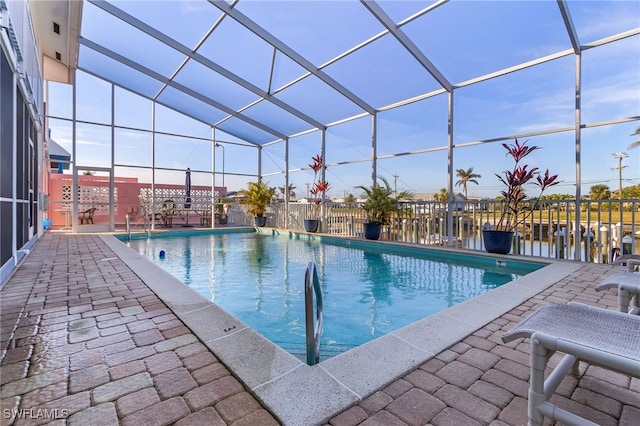 view of swimming pool featuring a lanai, a patio area, and a water view