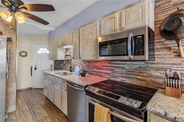 kitchen featuring dark wood-type flooring, sink, stainless steel appliances, light stone countertops, and decorative backsplash