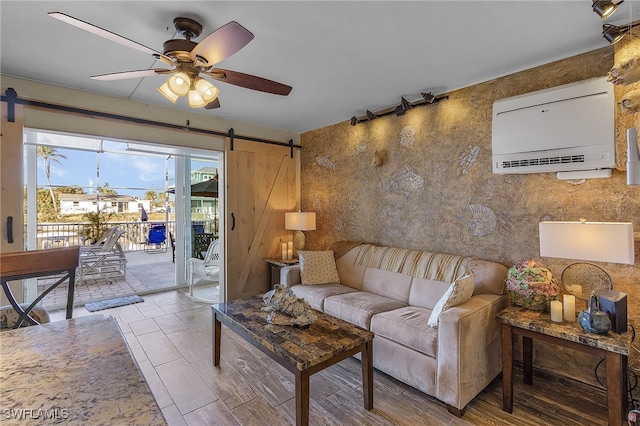 living room featuring ceiling fan, a barn door, and a wall mounted AC