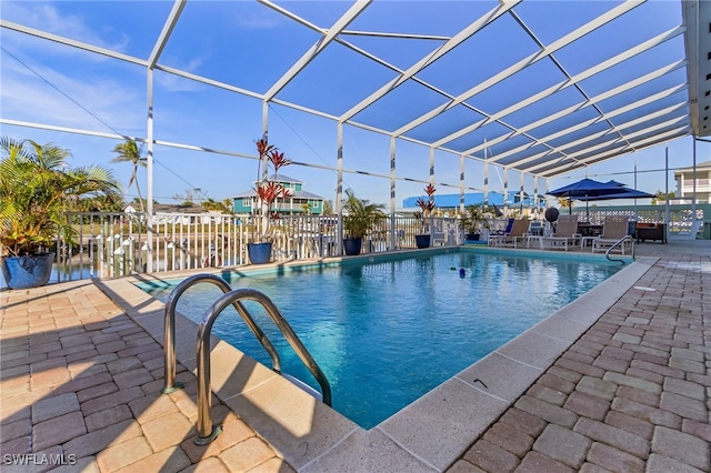 view of swimming pool featuring a patio, a water view, and glass enclosure