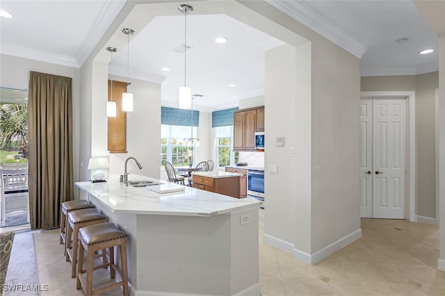 kitchen with light stone counters, decorative light fixtures, ornamental molding, and kitchen peninsula