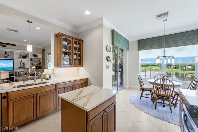 kitchen featuring sink, a water view, a center island, ornamental molding, and pendant lighting