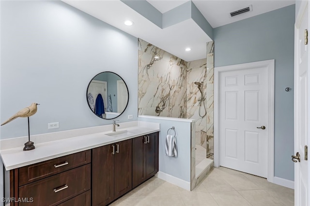 bathroom with tile patterned flooring, vanity, and a tile shower