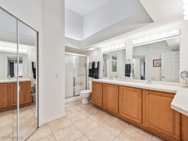 bathroom with tile patterned flooring, vanity, a shower with shower door, and toilet