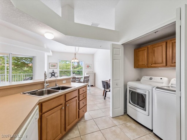 laundry area featuring washing machine and dryer, sink, light tile patterned floors, and an inviting chandelier