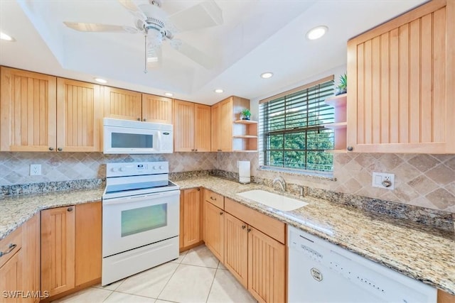 kitchen with sink, white appliances, light stone countertops, and a tray ceiling