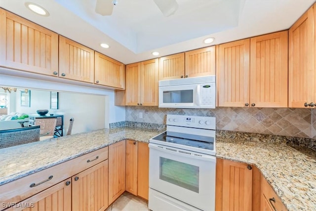 kitchen featuring white appliances, light stone countertops, and decorative backsplash