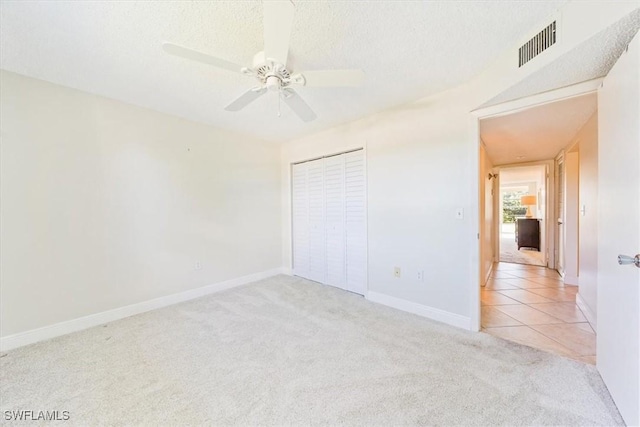 unfurnished bedroom with light carpet, a closet, ceiling fan, and a textured ceiling