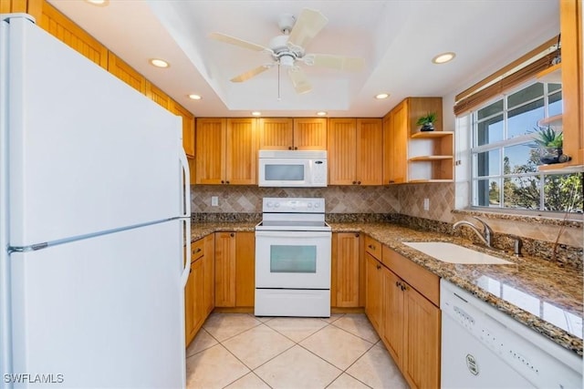 kitchen with white appliances, light stone countertops, light tile patterned flooring, a tray ceiling, and sink