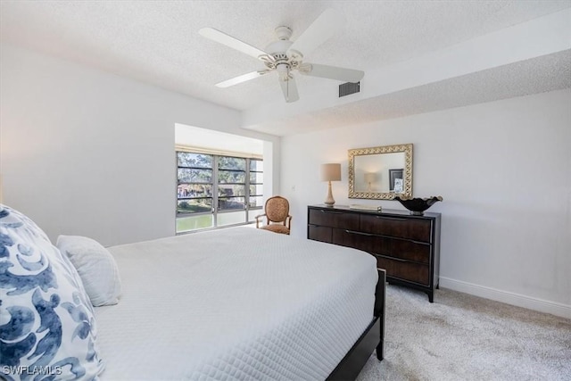 bedroom featuring a textured ceiling, light colored carpet, and ceiling fan