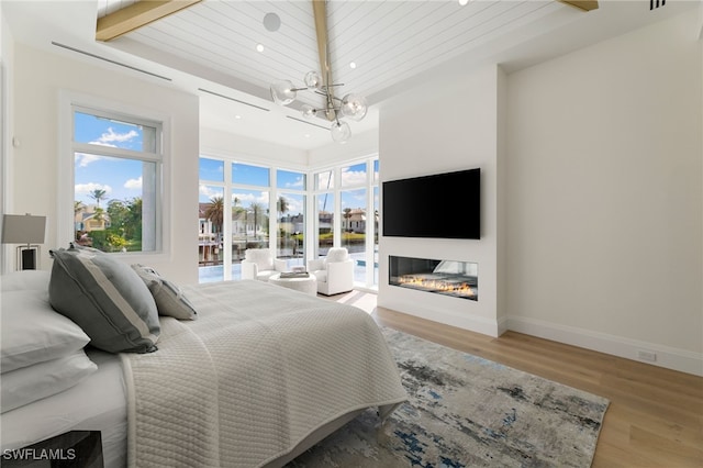 bedroom with wood ceiling, an inviting chandelier, light hardwood / wood-style floors, access to outside, and beamed ceiling