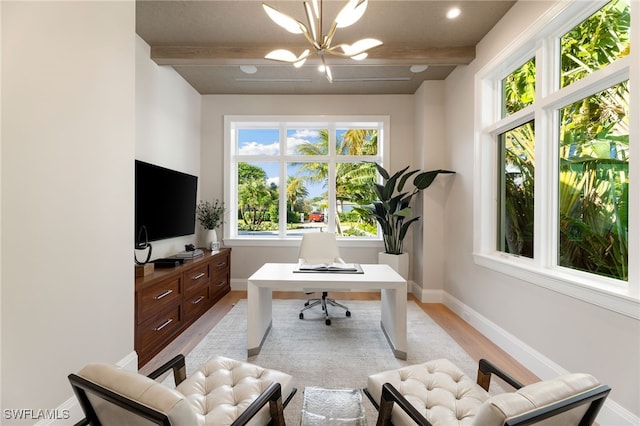 office space featuring light wood-type flooring, a notable chandelier, and beam ceiling