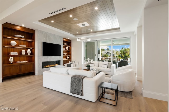 living room with wood ceiling, light hardwood / wood-style floors, a raised ceiling, a premium fireplace, and built in shelves