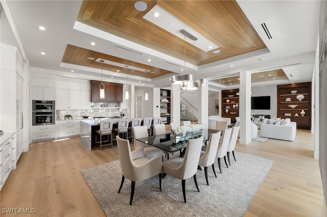 dining area featuring light hardwood / wood-style flooring and a raised ceiling