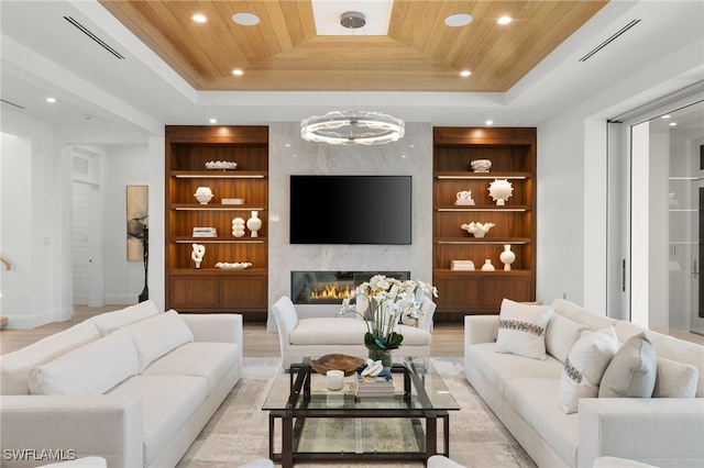 living room with a premium fireplace, built in shelves, wooden ceiling, and a raised ceiling