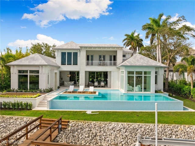 rear view of house with a fenced in pool, a yard, a patio area, and a balcony
