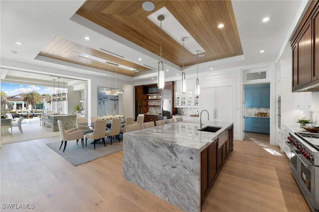 kitchen with decorative light fixtures, sink, backsplash, and a tray ceiling