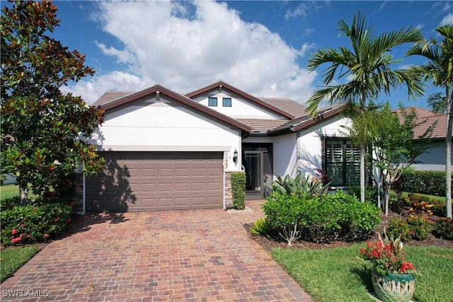 view of front facade with stucco siding, an attached garage, and decorative driveway