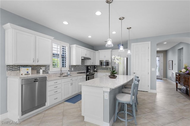 kitchen featuring stainless steel appliances, a sink, arched walkways, tasteful backsplash, and recessed lighting