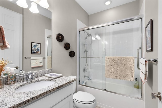 bathroom with shower / bath combination with glass door, vanity, and toilet