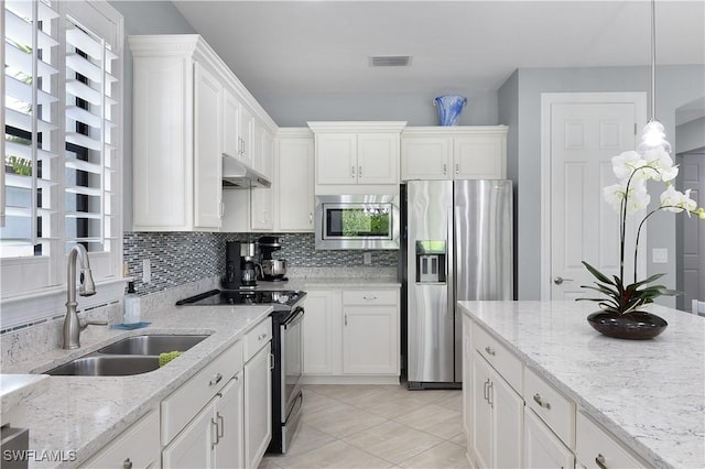 kitchen featuring appliances with stainless steel finishes, a sink, under cabinet range hood, white cabinets, and backsplash