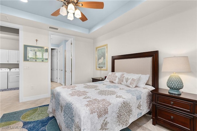 bedroom with washing machine and clothes dryer, light tile patterned floors, ceiling fan, baseboards, and a raised ceiling