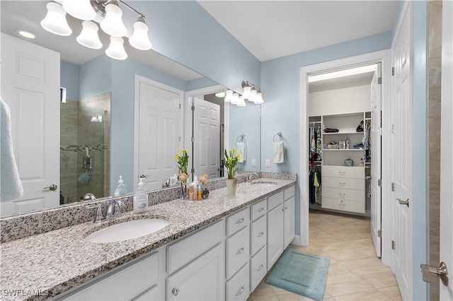 full bath with a stall shower, tile patterned floors, double vanity, a walk in closet, and a chandelier