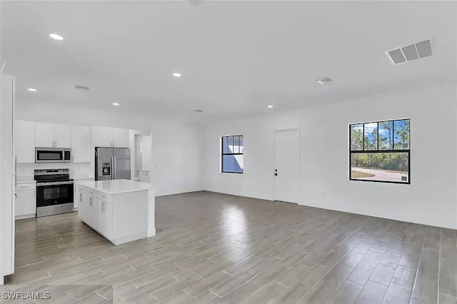 kitchen featuring white cabinetry, appliances with stainless steel finishes, a center island, and light hardwood / wood-style flooring