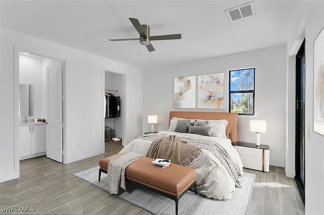 bedroom featuring a walk in closet, connected bathroom, ceiling fan, and a closet