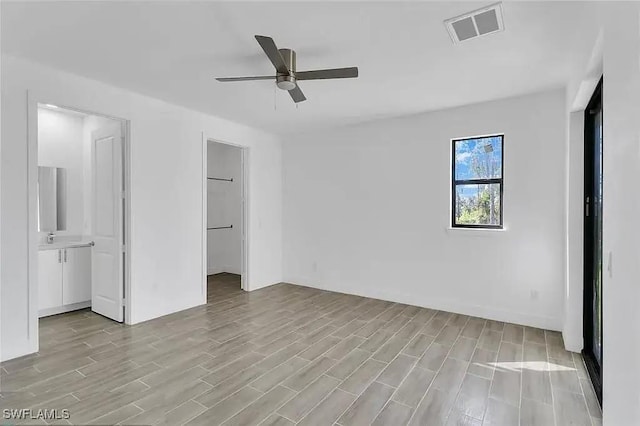 unfurnished bedroom with sink, a walk in closet, ceiling fan, light hardwood / wood-style floors, and a closet