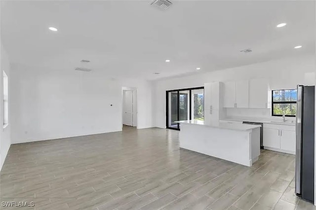 kitchen featuring sink, light hardwood / wood-style flooring, appliances with stainless steel finishes, a center island, and white cabinets