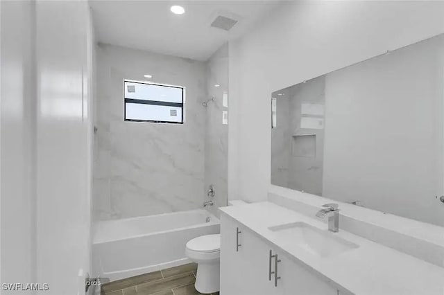 full bathroom featuring vanity, tiled shower / bath combo, and toilet