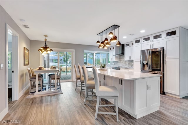 kitchen featuring white cabinets, a kitchen island, pendant lighting, and stainless steel fridge