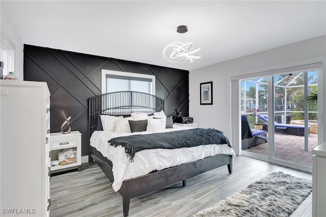 bedroom with light hardwood / wood-style flooring, a notable chandelier, and access to outside