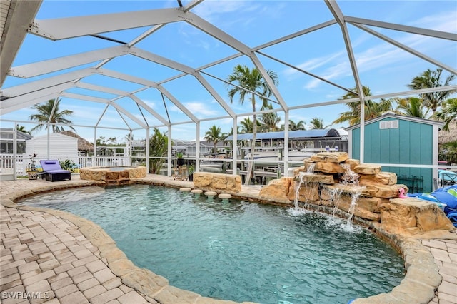 view of swimming pool featuring a patio, an in ground hot tub, a lanai, pool water feature, and a storage shed