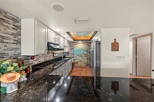 kitchen with visible vents, under cabinet range hood, a sink, stainless steel fridge, and black electric cooktop