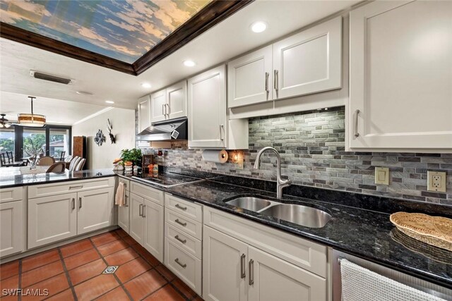 kitchen with tasteful backsplash, dark stone counters, sink, and white cabinets