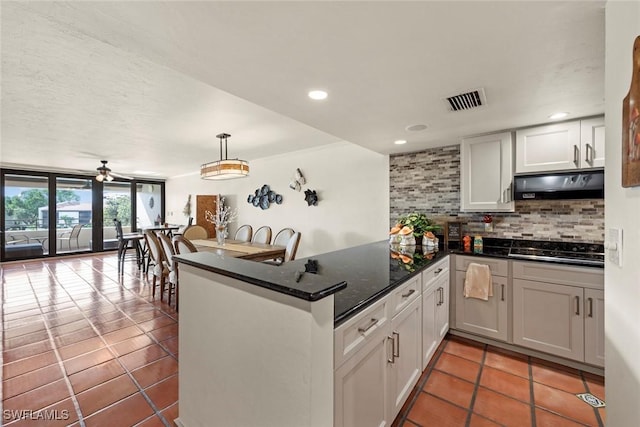 kitchen featuring tasteful backsplash, hanging light fixtures, kitchen peninsula, white cabinets, and black stovetop