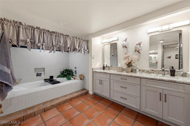 full bath with tile patterned flooring, double vanity, a relaxing tiled tub, and a sink