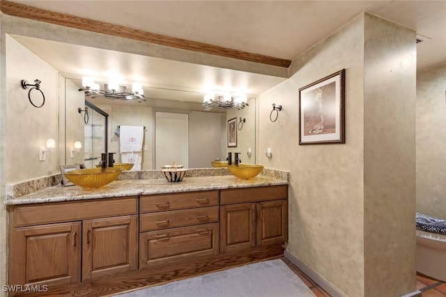 bathroom featuring double vanity, baseboards, and a sink