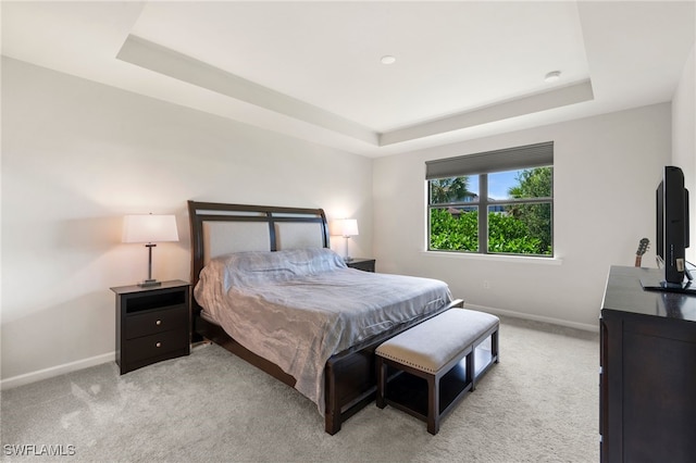 bedroom featuring a tray ceiling and light colored carpet