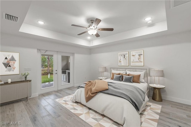 bedroom with french doors, ceiling fan, a tray ceiling, and access to outside