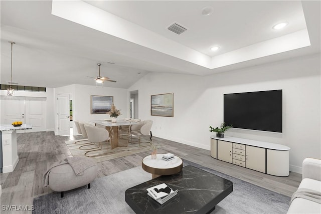 living room with hardwood / wood-style floors, ceiling fan, and a tray ceiling