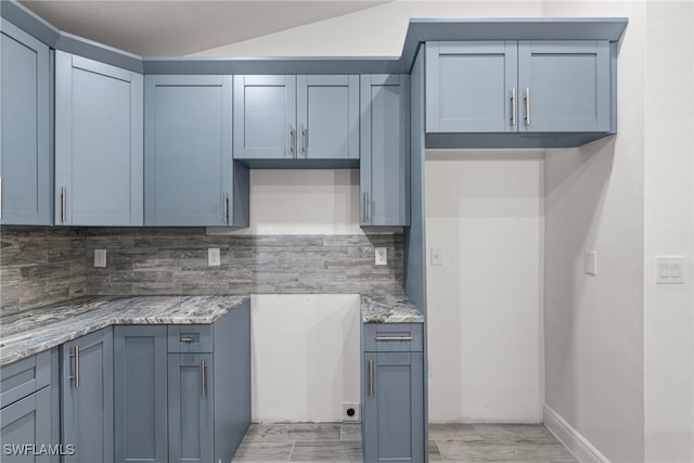 kitchen featuring light stone countertops, light hardwood / wood-style floors, and decorative backsplash