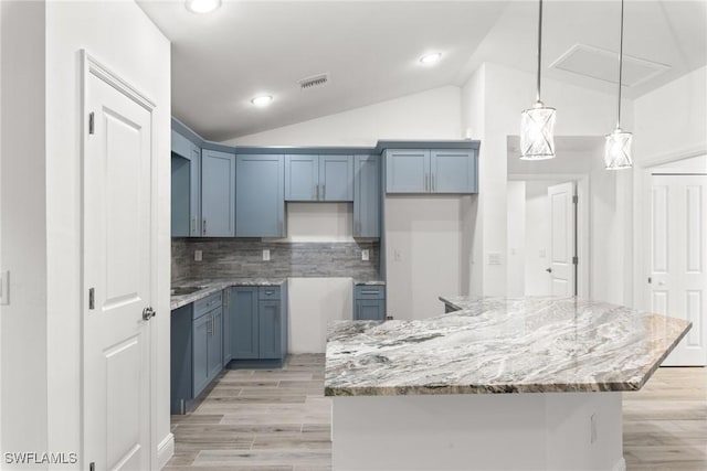 kitchen with backsplash, decorative light fixtures, vaulted ceiling, and a kitchen island